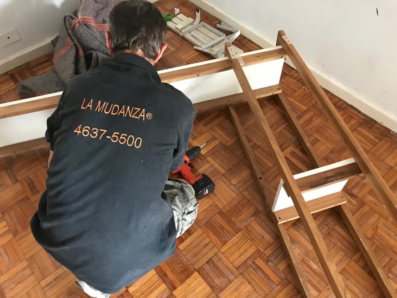 Técnico de La Mudanza armando cama con taladro en departamento de Buenos Aires